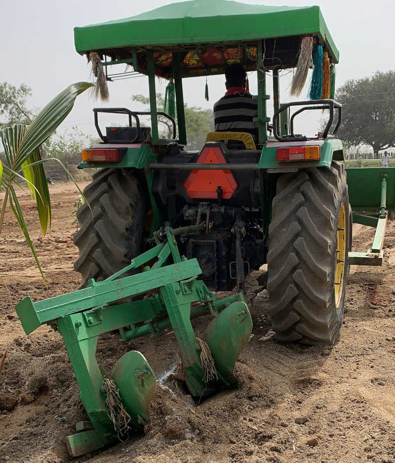 Tractor with a plough, seen from behind