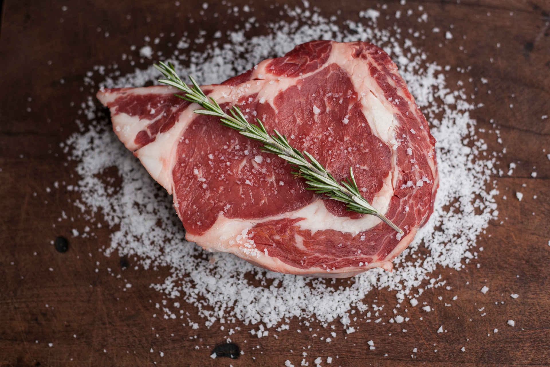 A steak with a sprig of rosemary, surrounded by plenty of salt, which in the context of this article can just as well be interpreted as sugar